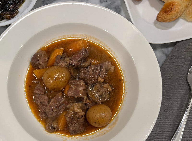Slow cooker boeuf bourguignon served in a white bowl, featuring tender chunks of beef, carrots, baby potatoes, and mushrooms in a rich red wine sauce, garnished with parsley.