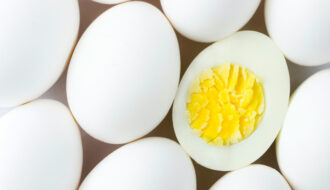 rows of hard boiled eggs lined up at an angle with one sliced open in the middle