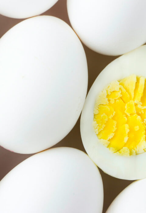 rows of hard boiled eggs lined up at an angle with one sliced open in the middle