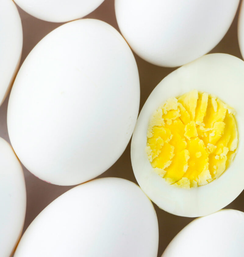 rows of hard boiled eggs lined up at an angle with one sliced open in the middle