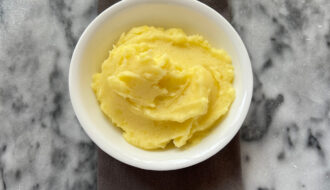 mashed potatoes recipe in white bowl on gray and white surface