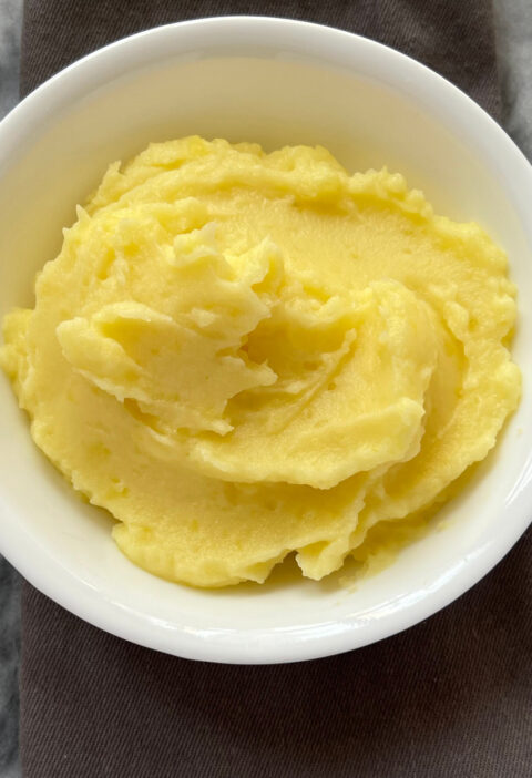 mashed potatoes recipe in white bowl on gray and white surface