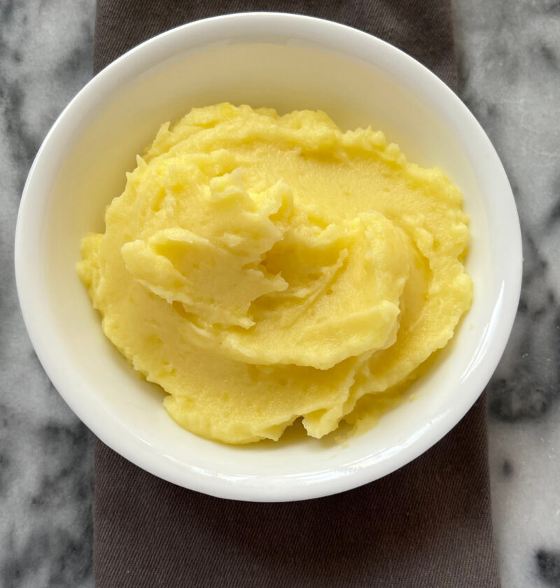 mashed potatoes recipe in white bowl on gray and white surface