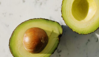 Ripe avocado halved on a cutting board, showing safe slicing technique to prevent avocado hand injuries