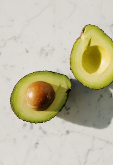 Ripe avocado halved on a cutting board, showing safe slicing technique to prevent avocado hand injuries