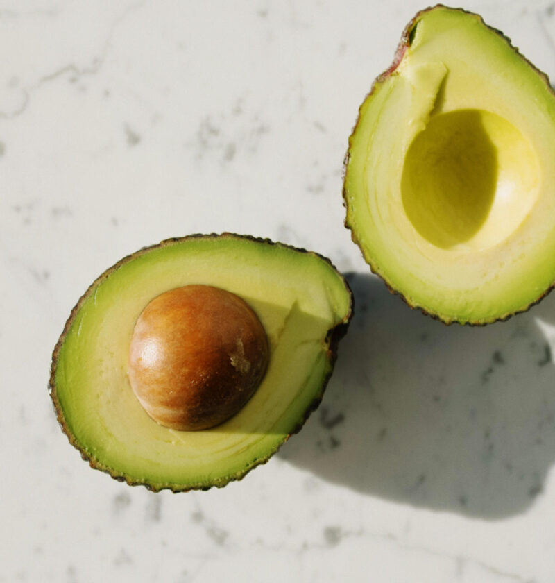 Ripe avocado halved on a cutting board, showing safe slicing technique to prevent avocado hand injuries