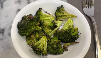 garlic roasted broccoli served in a white bowl on a marble surface