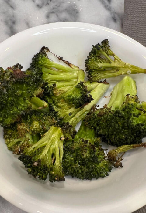 garlic roasted broccoli served in a white bowl on a marble surface