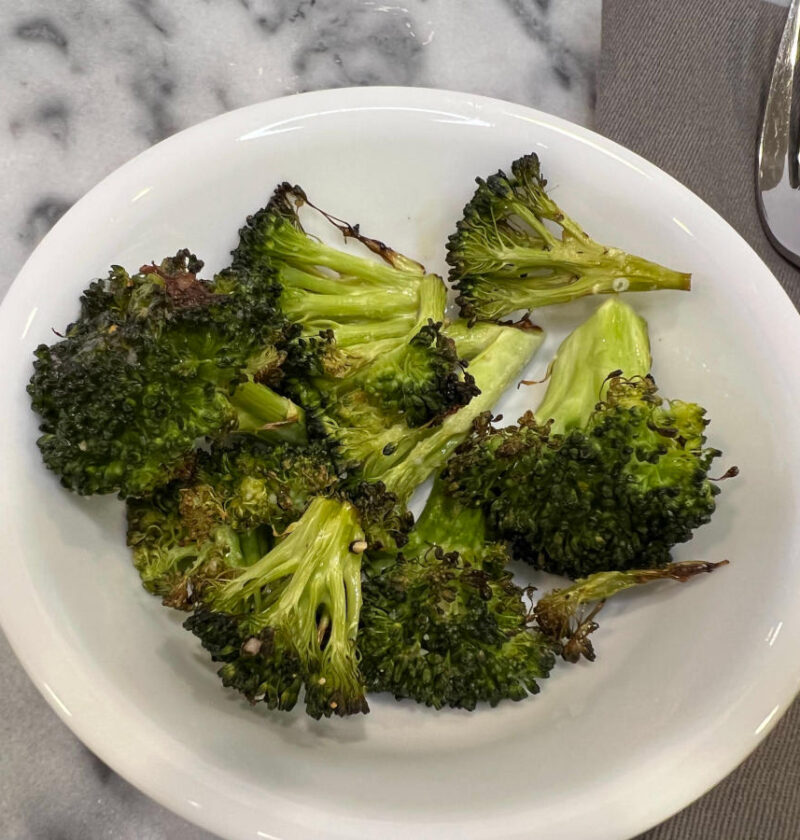 garlic roasted broccoli served in a white bowl on a marble surface
